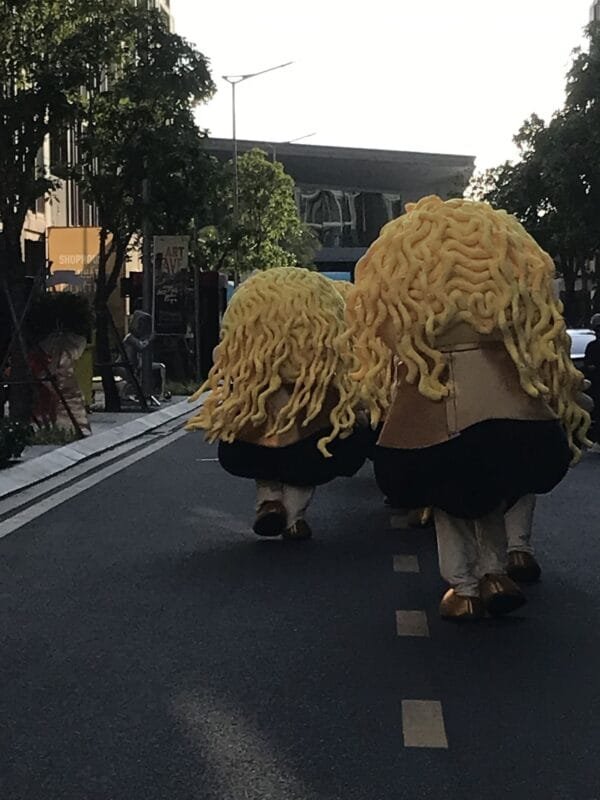 Costumed figures walking down a street.